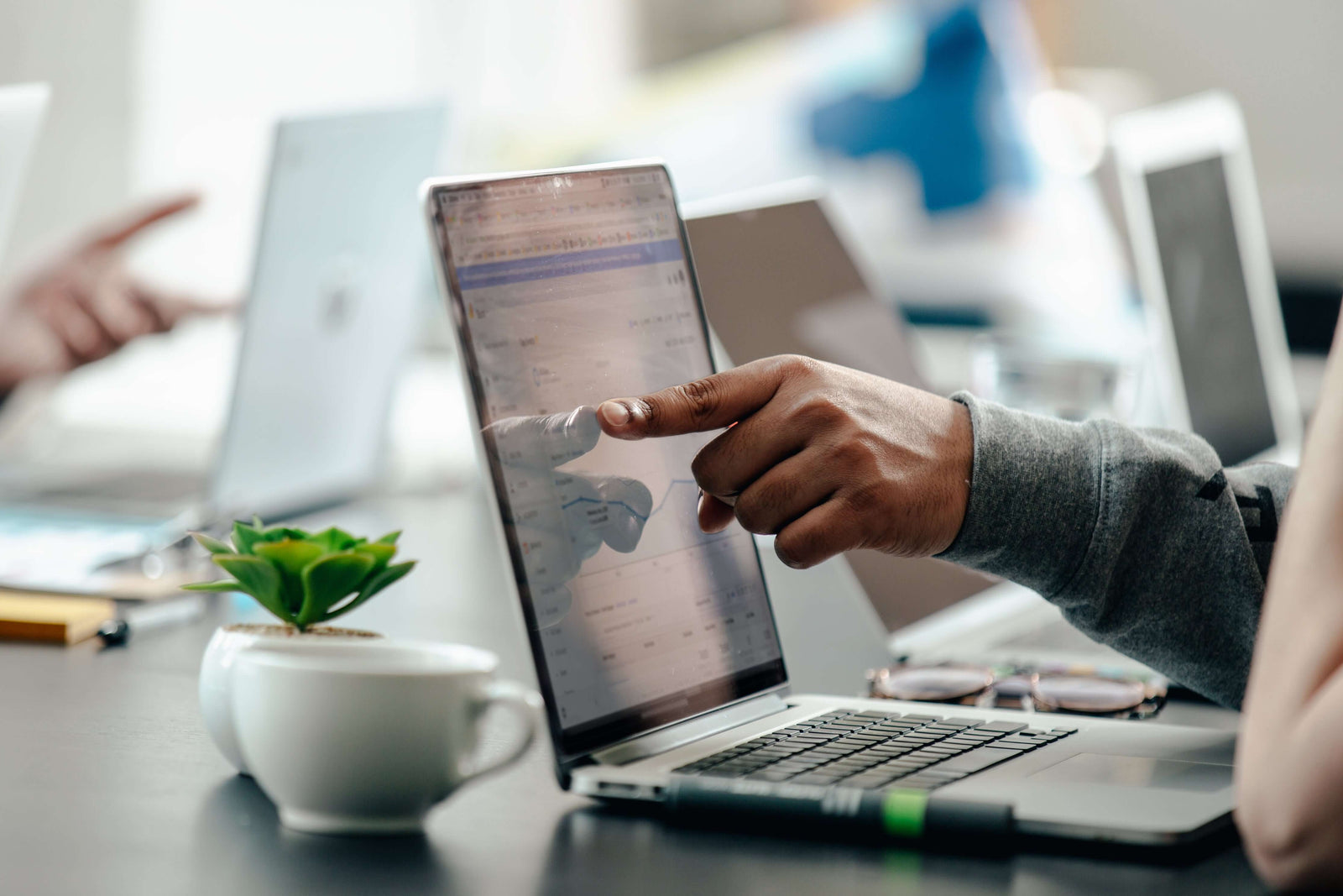 Person pointing at graph on laptop screen