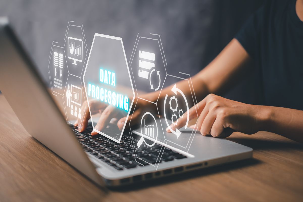 Someone working on a computer with a hologram of data processing icons on top of it