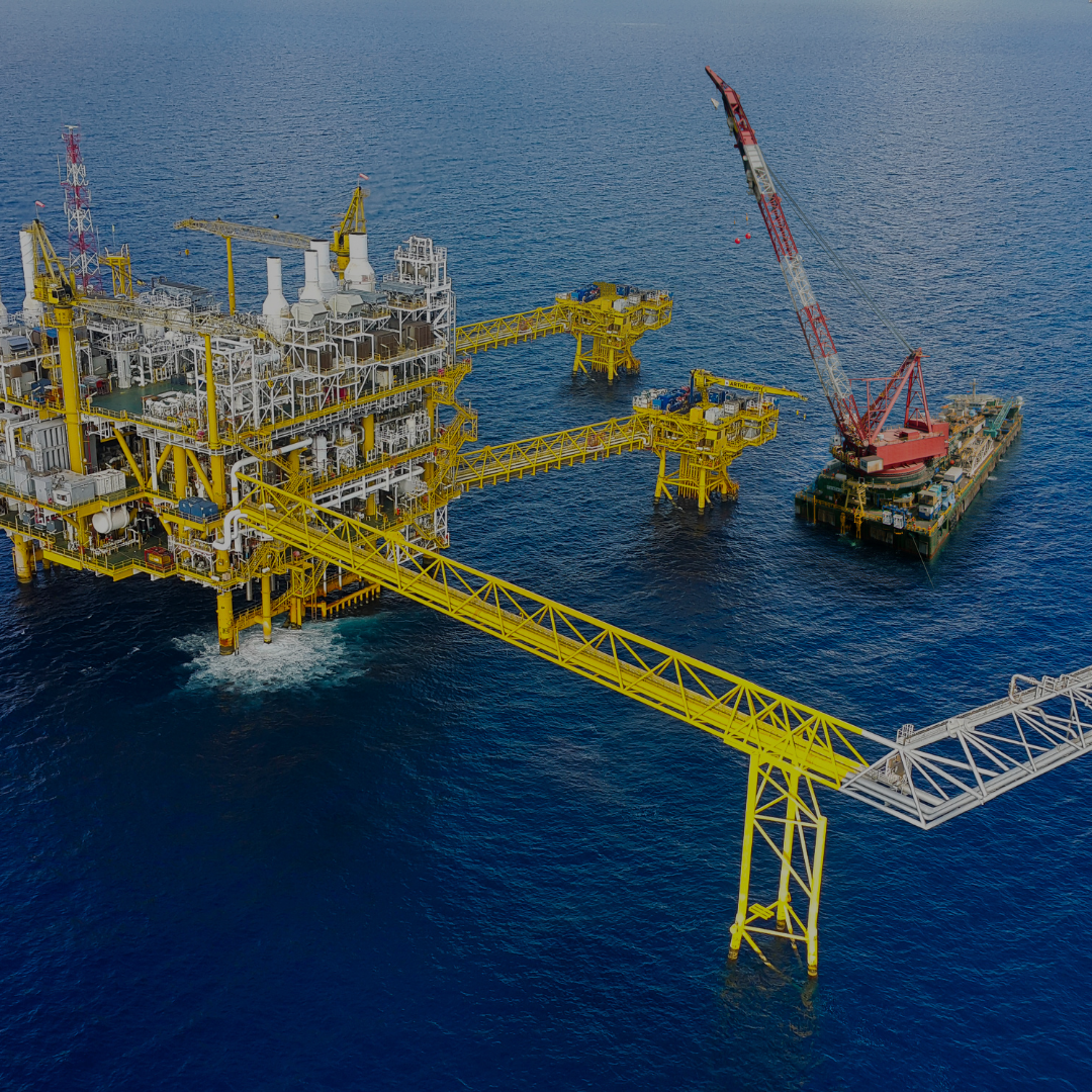 Aerial view of an offshore oil platform with a crane in the ocean.
