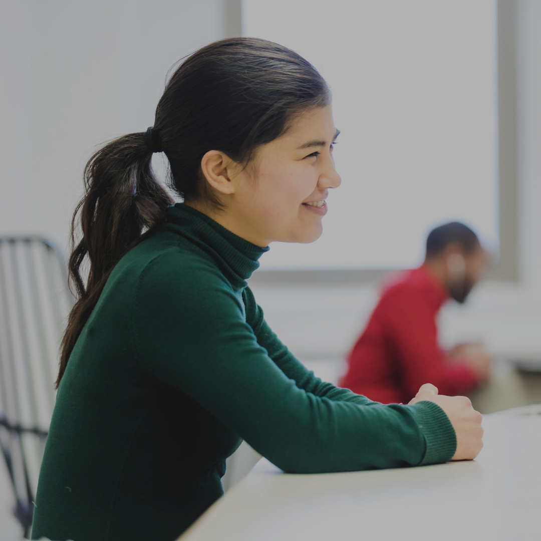A young Women sitting a desk smiling